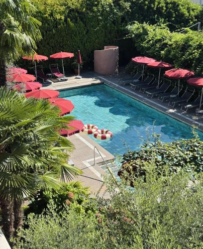 a swimming pool with red umbrellas and chairs at Hotel Gartenresidence Zea Curtis in Merano