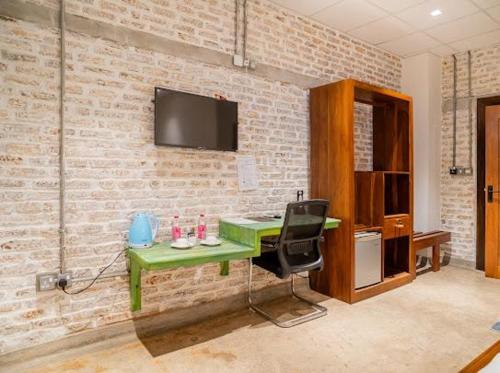 a green desk with a chair and a television on a brick wall at Ceylon Kingsmen Garden - Katunayake Airport Transit Hotels in Negombo