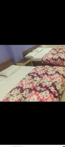 a close up of a bed with a floral blanket at Resort park view kathiyawadi matheran in Matheran