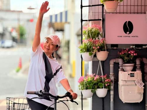 a woman riding a bike with her hand in the air at KOBE coffee hostel in Kobe