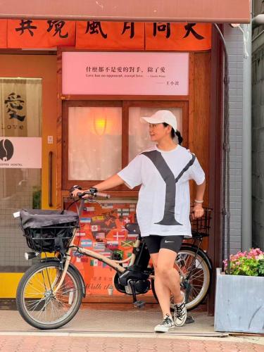 a man walking a bike in front of a store at KOBE coffee hostel in Kobe
