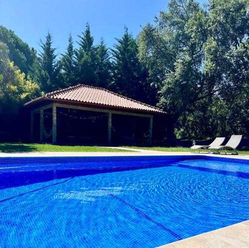 a swimming pool with two chairs and a house at Casa de Férias in Villa Nogueira
