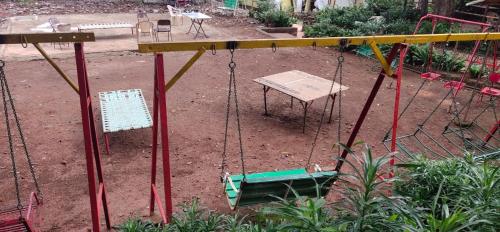 a swing set in a playground with a bench at Kathiyawadi Resort park view matheran in Matheran