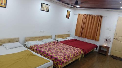 two beds sitting next to each other in a room at Kathiyawadi Resort park view matheran in Matheran