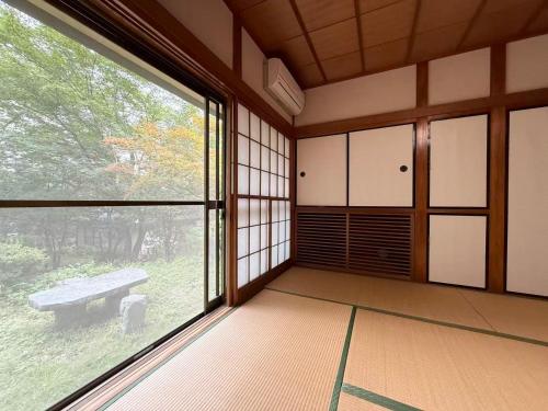 an empty room with a large window and a bench at 楓リゾート鬼怒川温泉 优雅宽敞的日式独栋旅馆 in Nikko