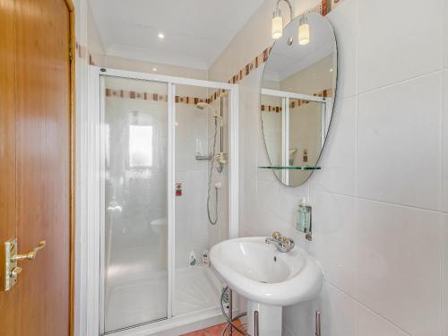 a white bathroom with a shower and a sink at Kilbride in Lamlash