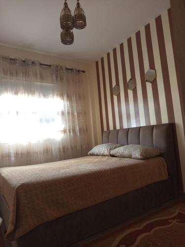 1 dormitorio con 1 cama con pared a rayas en Joli appartement 2 chambres à Agadir, en Agadir