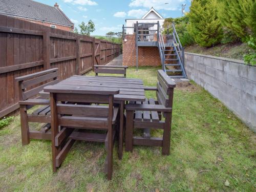 a wooden table and two chairs sitting next to a fence at Station House in St Bees