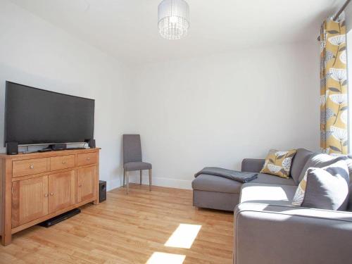 a living room with a couch and a flat screen tv at Fox Lodge in Crantock