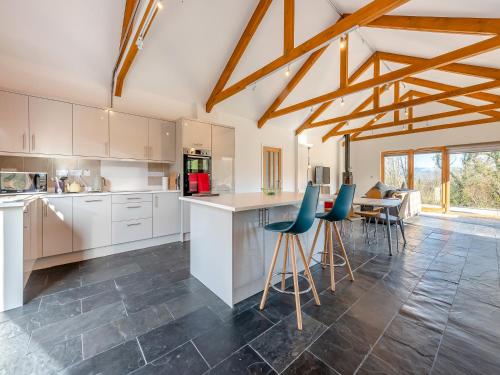 a kitchen with white cabinets and blue chairs at Pyllaubach in Llandeilo
