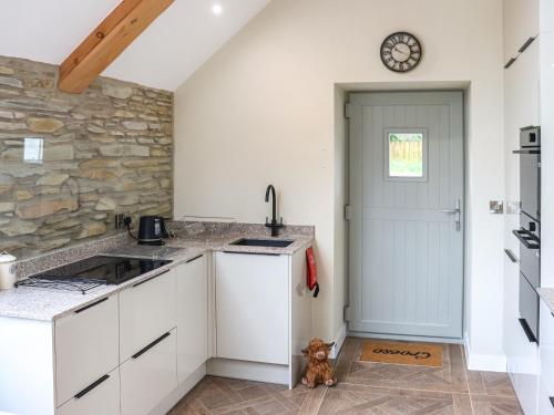 a kitchen with white cabinets and a clock on the door at Y Felin in Llandissilio