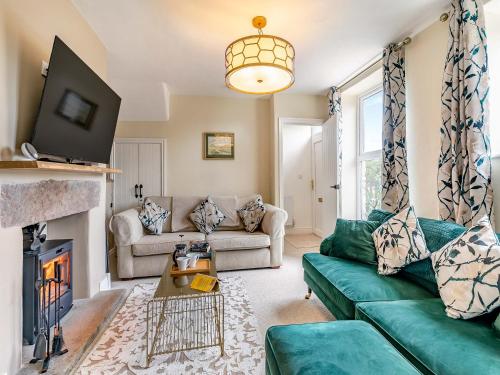 a living room with a green couch and a fireplace at Willoways in Bakewell