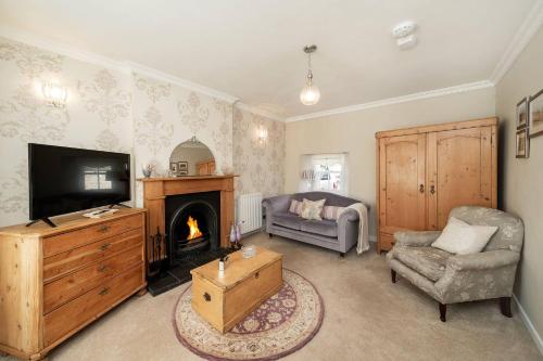 a living room with a fireplace and a television at Thrums Cottage in Kirriemuir