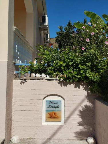 a sign on the side of a building with flowers at House Kochyli in Kefallonia