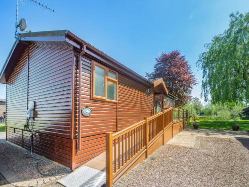 a wooden cabin with a wooden fence around it at Willowbank Lodge in Stratford-upon-Avon