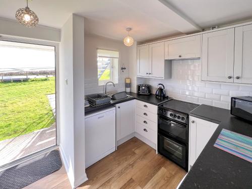 a kitchen with white cabinets and a black stove top oven at Primrose Apartment - Uk49291 in Woolfardisworthy