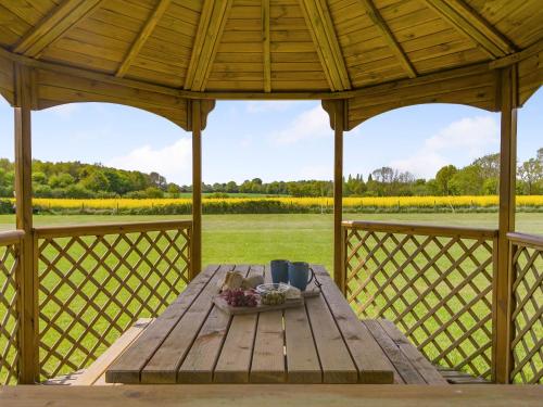a wooden table on a gazebo with a view of a field at Chestnut Tree Barn in Saint Lawrence