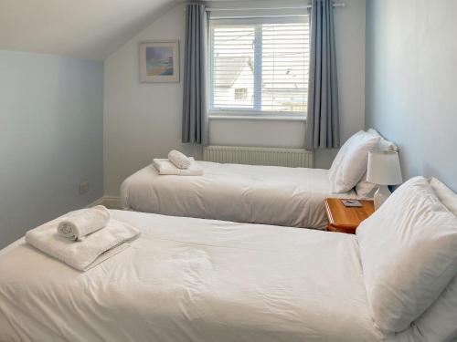 een slaapkamer met twee bedden met handdoeken erop bij Chy An Mordros in Hayle