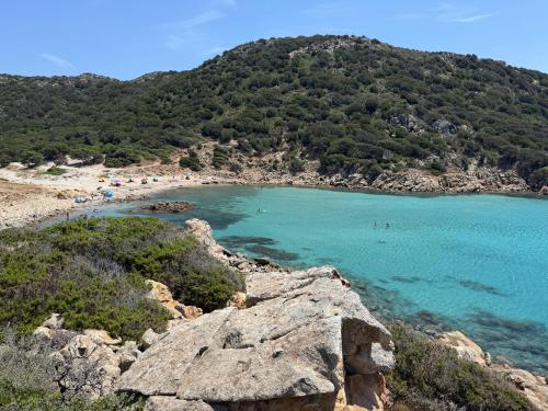 a beach with a bunch of people in the water at dépendance President villa Tuerredda in Chia