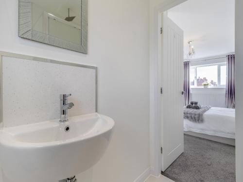 a white bathroom with a sink and a bedroom at The Old School House in Barnsley