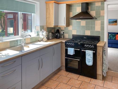 a kitchen with a stove and a sink at Kastania in Bere Regis