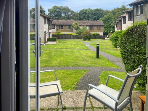 zwei Stühle in einem Fenster mit Blick auf einen Hof in der Unterkunft Strawberry Hill in Hayle