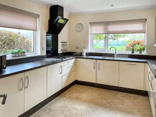 a kitchen with white cabinets and a sink and two windows at Autumn Leaves in Keswick