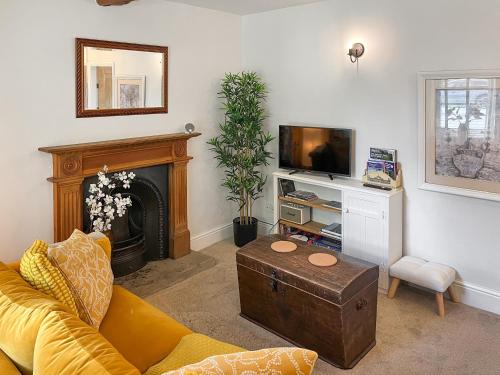a living room with a couch and a tv at Wisteria Cottage in Harrogate