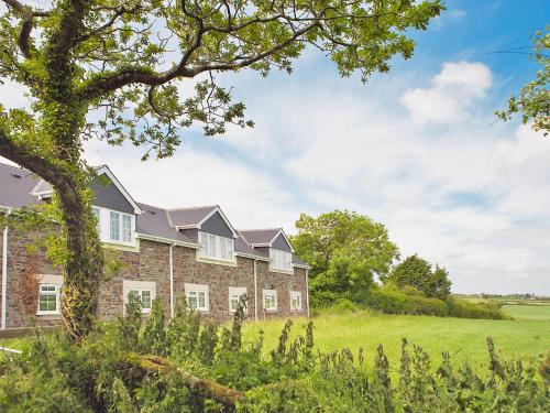 a large brick building with a grassy field in front at Hawfinch Apartment - Uk49304 in Woolfardisworthy