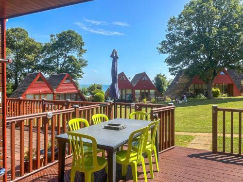 a wooden deck with a table and yellow chairs at Chalet 47 By The Sea in Kingsdown