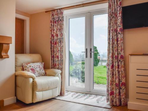 une chaise devant une porte coulissante en verre dans l'établissement Petals Cottage, à Lullington