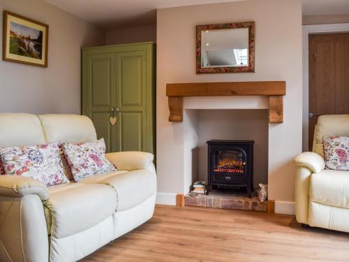 un salon avec un canapé et une cheminée dans l'établissement Petals Cottage, à Lullington
