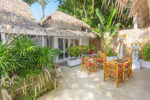 un patio con mesas y sillas frente a una casa en The White Cottage, en Bophut 