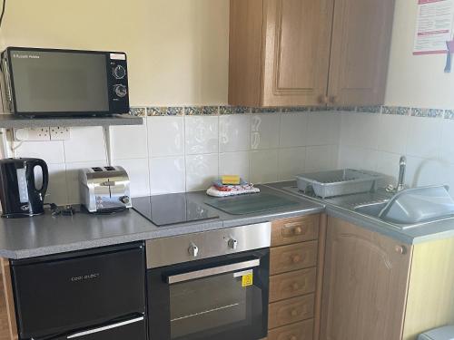 eine Küche mit einer Spüle, einem Herd und einer Mikrowelle in der Unterkunft Chestnut Apartment - Uk49277 in Woolfardisworthy