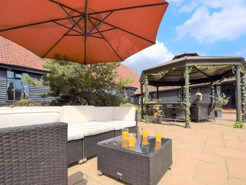 a patio with a couch and an umbrella and a gazebo at Doves Barn in Needham Market