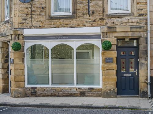 a store window with a blue door on a building at The Old Post Office - Uk49450 in Haltwhistle