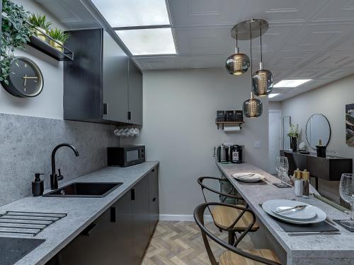 a kitchen with a sink and a counter with chairs at The Old Post Office - Uk49450 in Haltwhistle