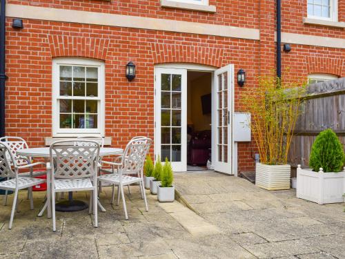 un patio con mesa y sillas frente a un edificio de ladrillo en The Mount View, en Towcester