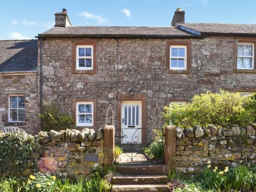 une ancienne maison en pierre avec une clôture en pierre dans l'établissement Rose Cottage, à Appleby