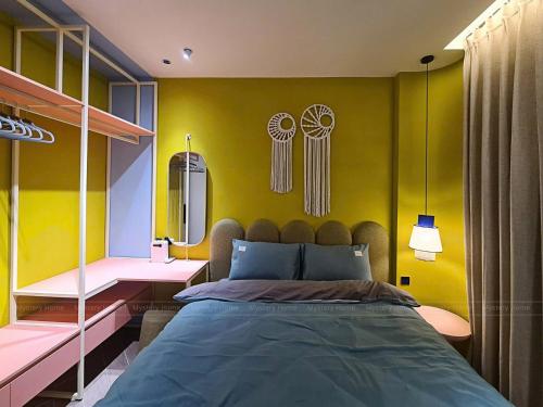 a bedroom with a bed and a yellow wall at Hoàng Gia villa Novaworld in Bình Sum