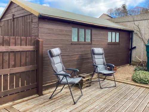 two chairs sitting on a deck next to a fence at Cosy Cottage By The Sea in Cromarty
