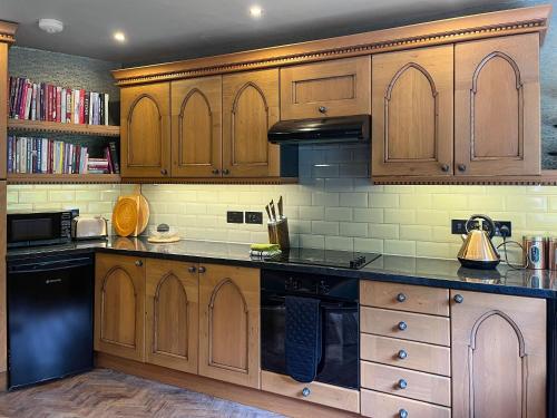 a kitchen with wooden cabinets and black appliances at Upper Double Lodge in Kirkcudbright