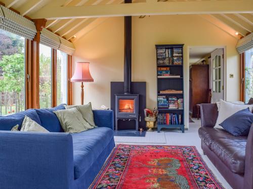 - un salon avec des canapés bleus et une cheminée dans l'établissement Lomond Cottage, à Garsington