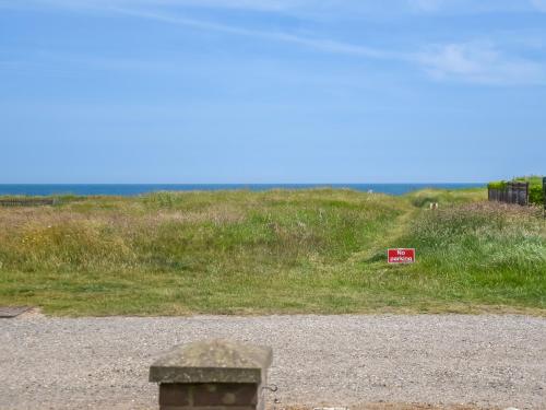 a sign on the side of a grassy hill at Beach Escape in Bacton