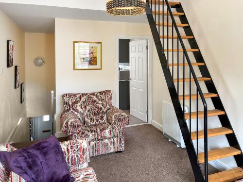 a living room with a chair and a staircase at Bank Top Mews - Uk49214 in Wilsden