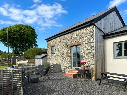 a stone building with chairs and a bench next to it at The Tractor Barn - Uk49678 in Bratton Fleming