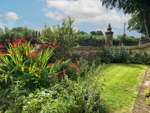 a garden with red flowers and a fence at The Gatehouse Beckfoot Hall in Great Musgrave