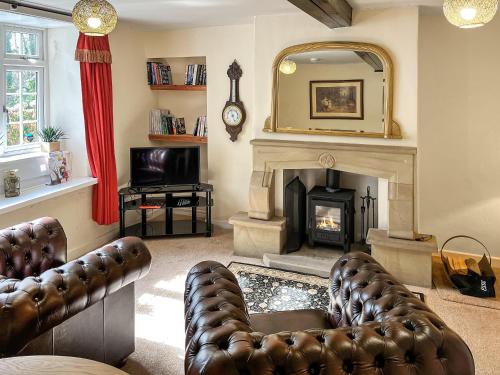 a living room with a fireplace and a mirror at Bank Top Cottage - Uk49215 in Wilsden