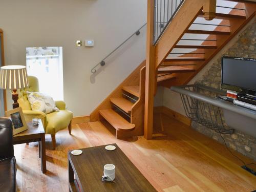 a living room with a staircase with a couch and a table at The Coach House The Old Rectory in Buckland St Mary
