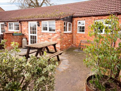a wooden picnic table in front of a brick building at Brown Snout in Ledbury